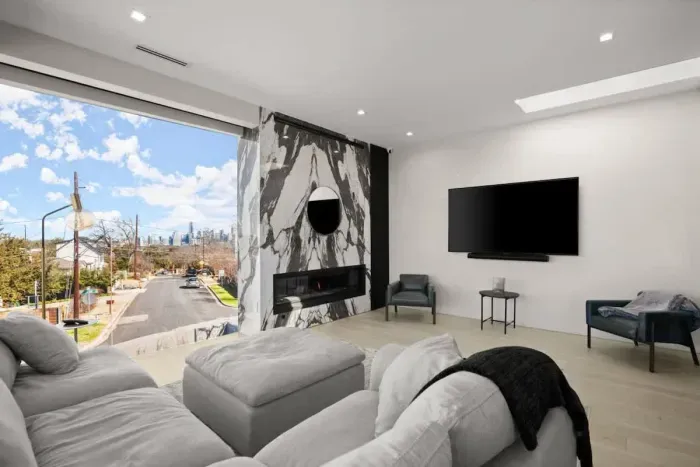 Unwind in a modern living space with floor-to-ceiling windows, fireplace, and a theater-style TV for the perfect night in