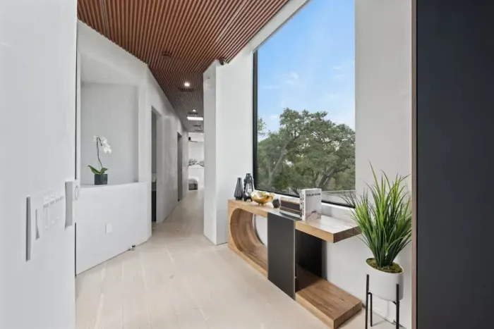 A beautifully styled hallway with natural light and treetop views creates a welcoming transition between spaces.