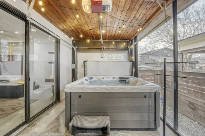 Private covered hot tub patio with string lights.
