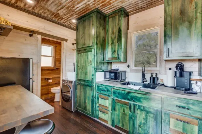 Step inside the cozy container, where compact design meets comfort. The space is thoughtfully arranged with clever storage solutions, a comfortable bed, and modern amenities, creating a warm and inviting atmosphere in a unique setting.