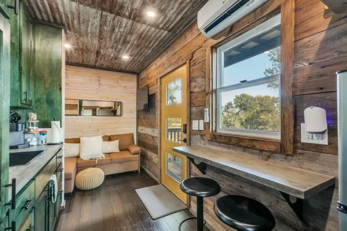 Step inside the cozy container, where compact design meets comfort. The space is thoughtfully arranged with clever storage solutions, a comfortable bed, and modern amenities, creating a warm and inviting atmosphere in a unique setting.