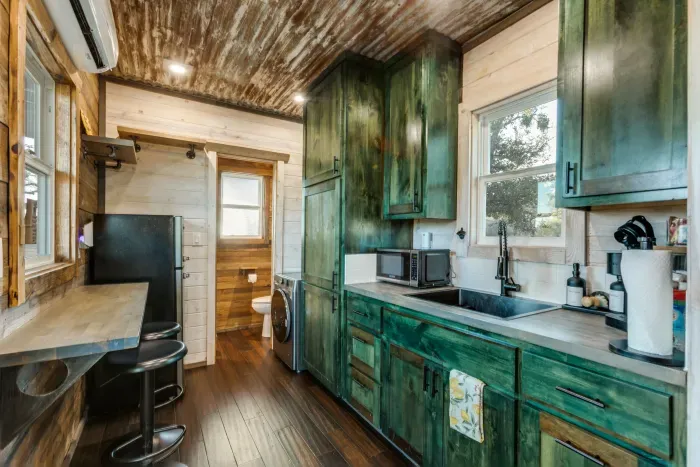 Step inside the cozy container, where compact design meets comfort. The space is thoughtfully arranged with clever storage solutions, a comfortable bed, and modern amenities, creating a warm and inviting atmosphere in a unique setting.