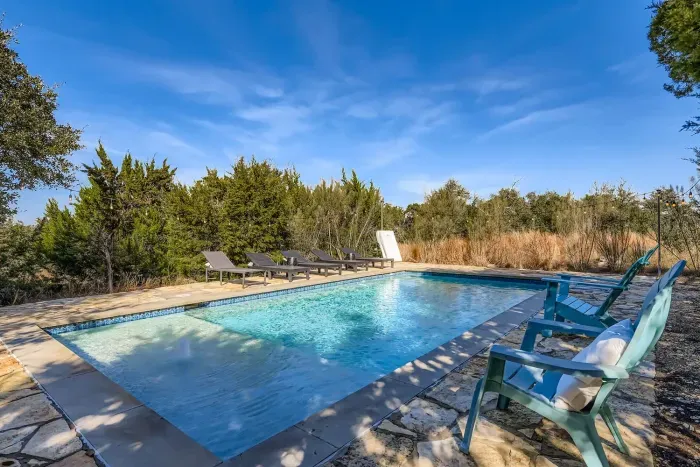Pool with sun loungers and trees.