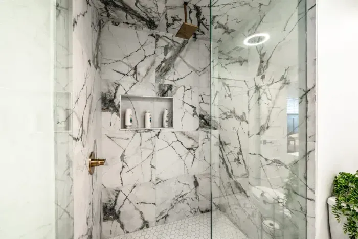 A luxurious rainfall shower surrounded by striking marble finishes.