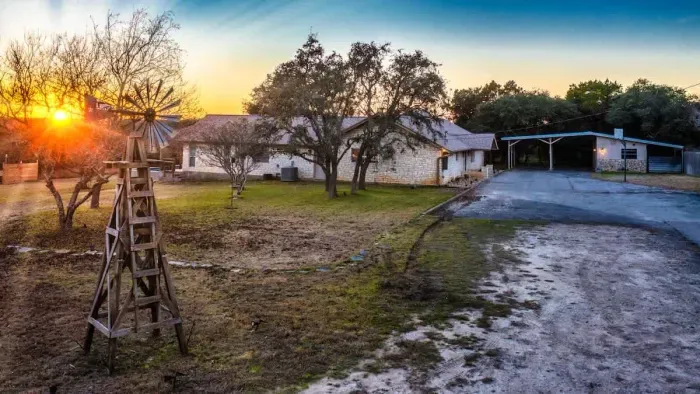 An expansive backyard framed by mature trees and golden sunset views.