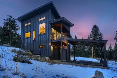 1. The side of the house during the winter months, with a light dusting of snow covering the ground and the surrounding greenery. The home stands warmly against the chilly air, showcasing its winter charm and inviting atmosphere.