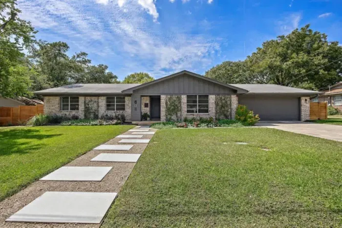 Stunning front exterior featuring a wide, welcoming entryway framed by neatly trimmed grasses. The well-maintained landscape enhances the curb appeal, offering a polished, inviting look. Perfectly balanced between modern elegance and natural beauty,