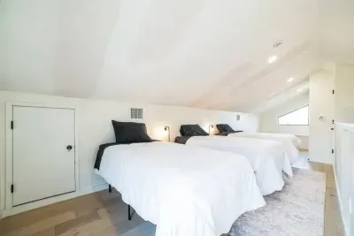 Family-friendly bedroom with three twin beds and simple decor, offering a restful night’s sleep and relaxation.