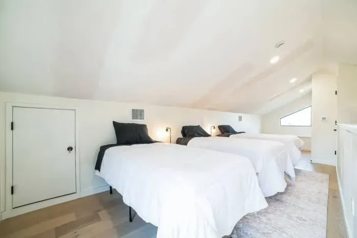 Family-friendly bedroom with three twin beds and simple decor, offering a restful night’s sleep and relaxation.