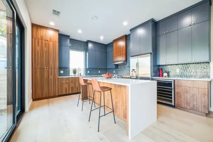 This modern kitchen is a harmonious blend of style and functionality, featuring sleek countertops, state-of-the-art appliances, and minimalist cabinetry. A large window or sliding glass doors provide an uninterrupted view of the sparkling pool.