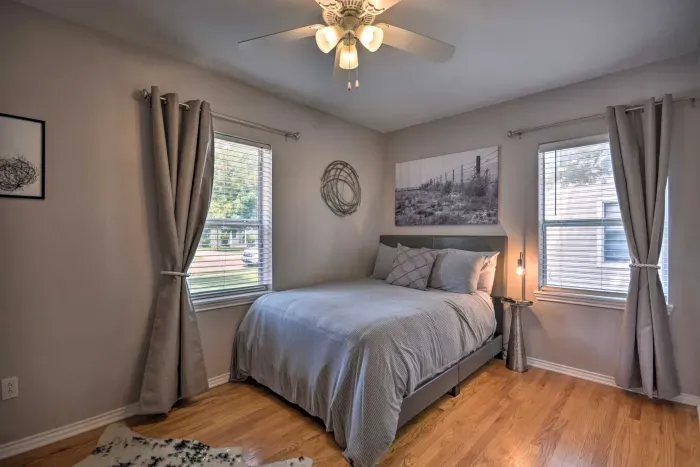 Bright guest bedroom with queen bed and large windows.
