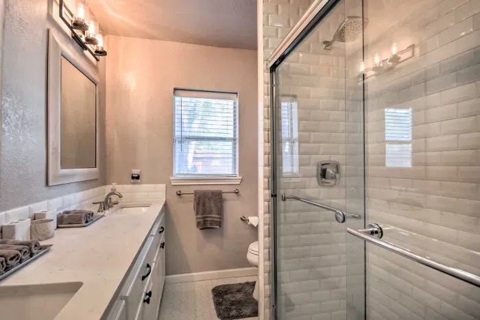 Walk-in shower with modern tile and bright lighting.