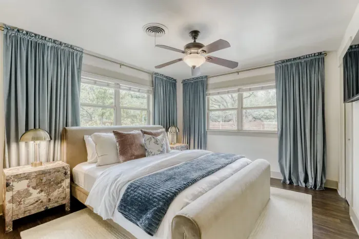 Bright and airy bedroom with soft tones, layered textures, and large windows that bring in natural light