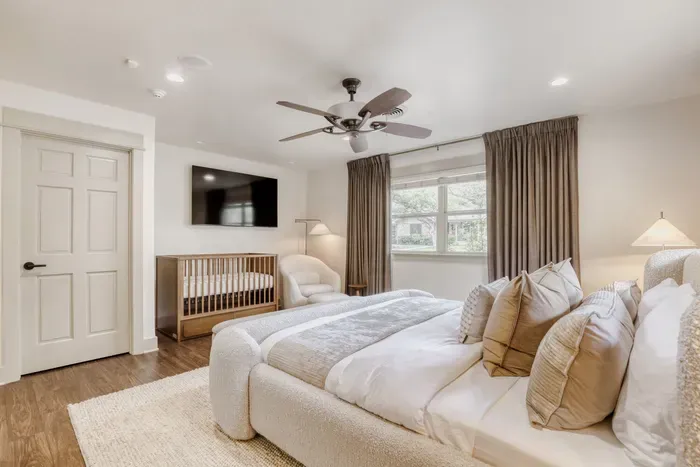 Light-filled primary bedroom featuring cozy seating and thoughtful design, blending comfort with quiet sophistication
