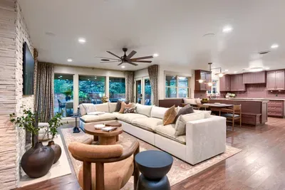 Bright living area anchored by a modern fireplace and large windows, bringing in natural light and easy indoor-outdoor living