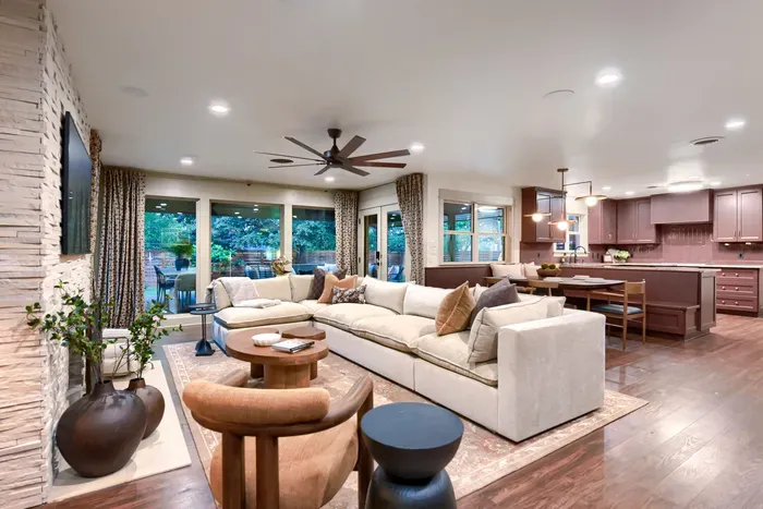 Bright living area anchored by a modern fireplace and large windows, bringing in natural light and easy indoor-outdoor living
