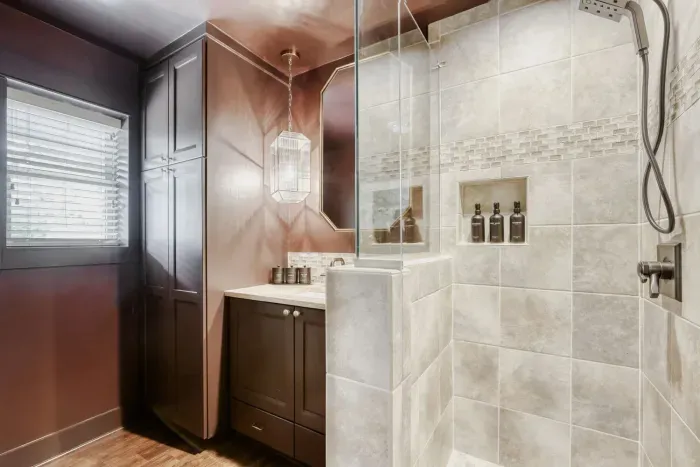 Stylish bathroom with rich, moody tones, custom cabinetry, and a sleek walk-in shower for a modern touch