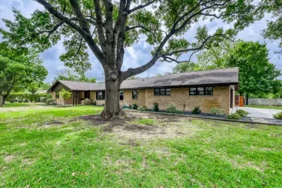 Classic brick exterior with expansive lawn space and beautiful tree coverage for added privacy