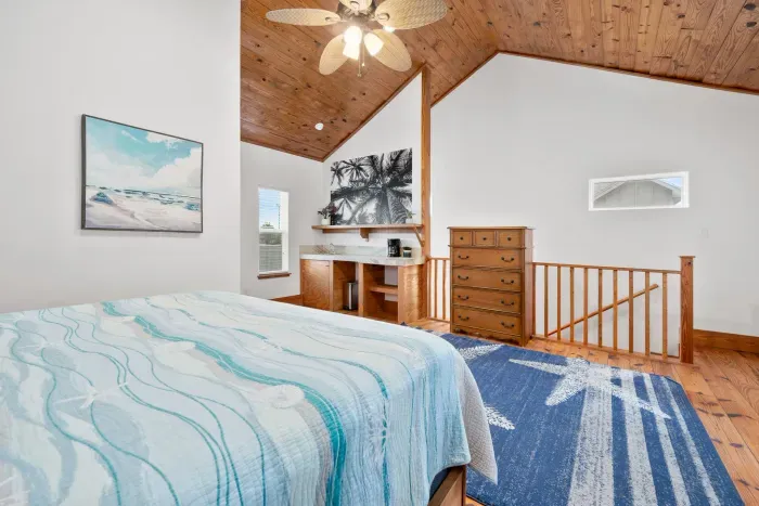 Bright bedroom with vaulted ceilings and serene coastal colors.