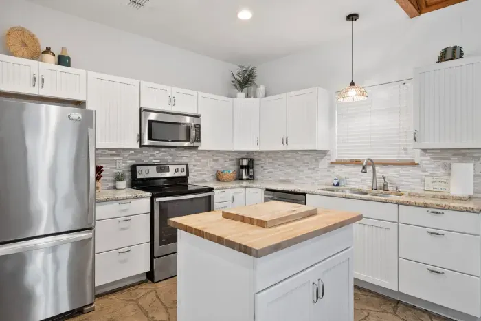 Crisp white kitchen with island prep space and stainless steel finishes.
