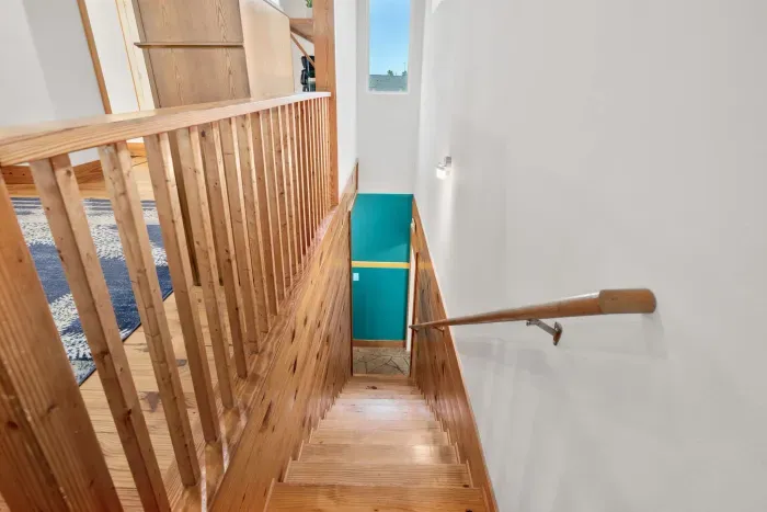 Warm wood staircase leading to the lower level, adding charm and character to your coastal retreat.