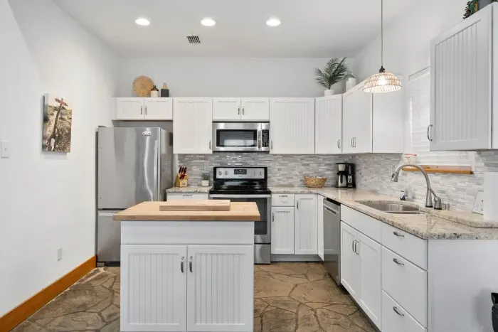 A beautifully updated kitchen featuring stainless steel appliances and elegant white cabinetry designed for effortless vacation cooking.