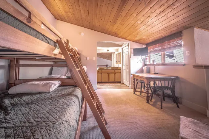 Large bunk room with seating area and warm wood accents.