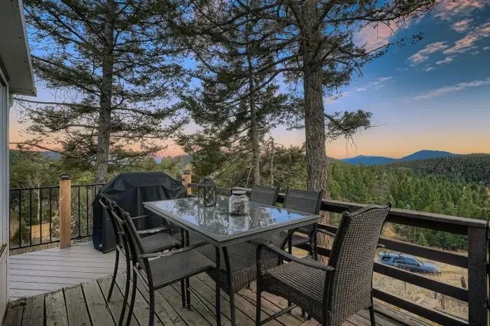 Balcony dining area overlooking forested hills and golden sunsets.