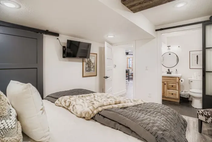 Elegant primary suite with TV, ensuite, and warm natural light.