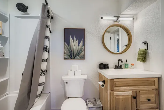 Modern bathroom with stylish tile and circular mirror.