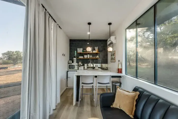 Pull-full sofa bed with to seats at the waterfall kitchen peninsula doubling as a workspace and cooking area