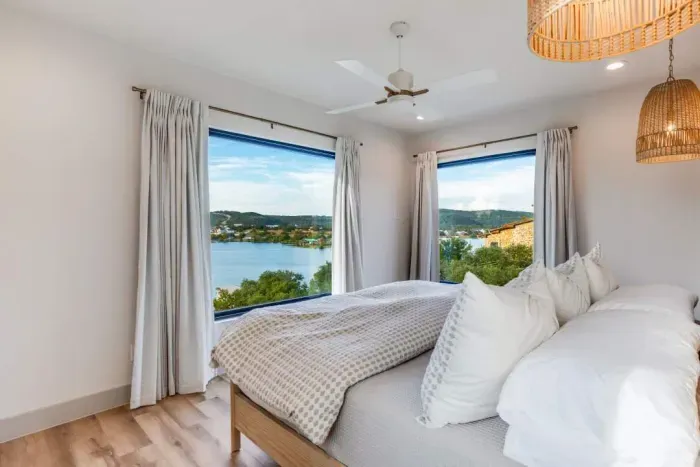 Bright bedroom with large windows framing peaceful lake views.