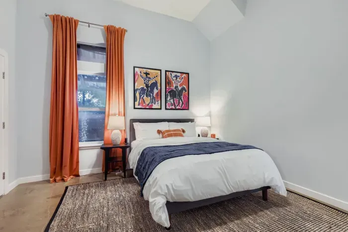Cozy bedroom with queen bed, colorful artwork, and natural light.