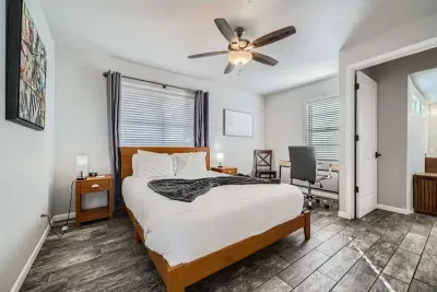 Enjoy a bright and airy bedroom, featuring large windows that flood the space with natural light. The room is fitted with blinds for privacy and light control, creating a fresh, inviting atmosphere for relaxation.