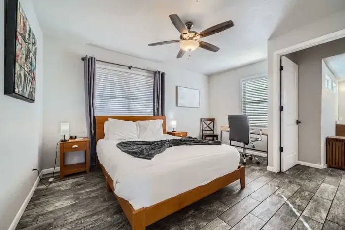 Enjoy a bright and airy bedroom, featuring large windows that flood the space with natural light. The room is fitted with blinds for privacy and light control, creating a fresh, inviting atmosphere for relaxation.