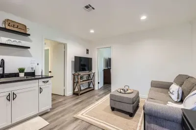 A stylish and inviting living area featuring a comfortable sofa, modern kitchen, and warm decor, creating the perfect space to unwind and feel at home.