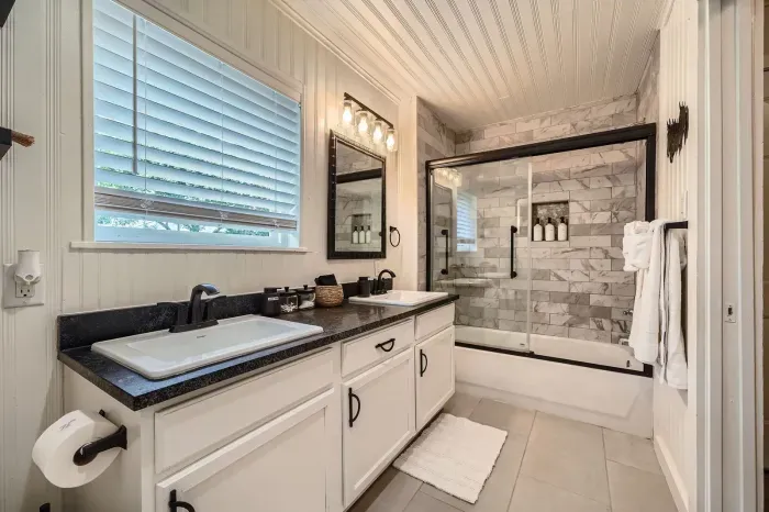 Bright full bathroom with double sinks and a spacious shower.