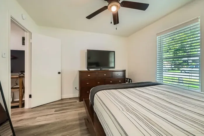 Another view of a guest-friendly bedroom with TV and dresser.