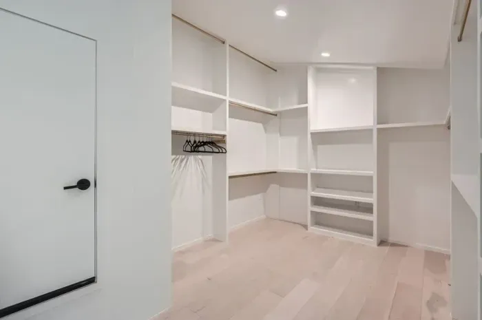Spacious and organized primary bedroom closet with built-in shelving and ample hanging space.