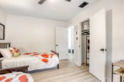Functional bedroom with two beds, dedicated workspace, and closet storage for longer visits