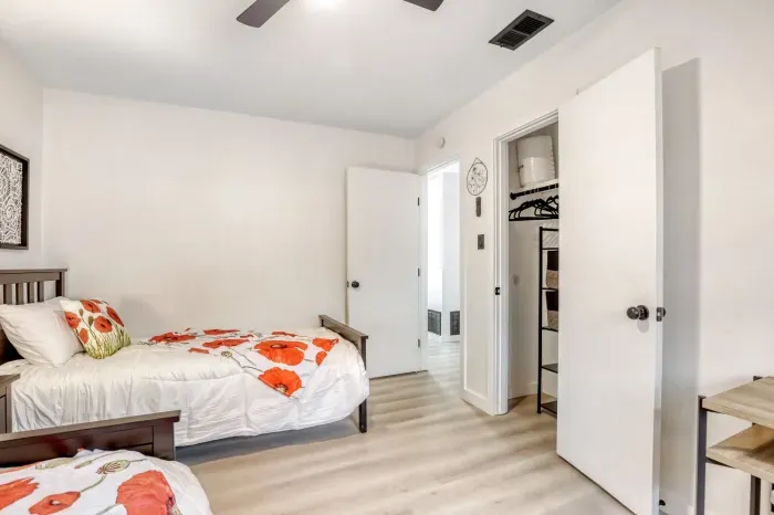 Functional bedroom with two beds, dedicated workspace, and closet storage for longer visits