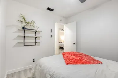 Bright, minimal bedroom with comfortable bed, blackout curtains, and dedicated space to unwind and recharge