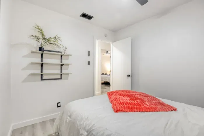 Bright, minimal bedroom with comfortable bed, blackout curtains, and dedicated space to unwind and recharge