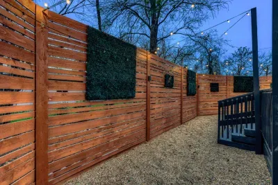 Fully fenced backyard with modern wood privacy panels and ambient lighting for a quiet, secluded feel