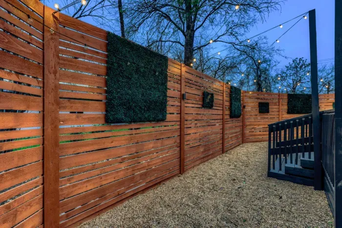Fully fenced backyard with modern wood privacy panels and ambient lighting for a quiet, secluded feel