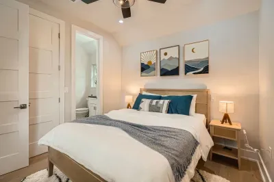 This minimalist room features a queen bed with crisp white linens, neutral decor, and a tranquil vibe for the perfect restful escape.