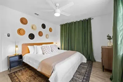 Cozy bedroom featuring a king-sized bed, blackout curtains for restful sleep, and unique hat décor that adds personality and style. The inviting atmosphere is perfect for unwinding, combining comfort with a touch of creative flair. A peaceful retreat