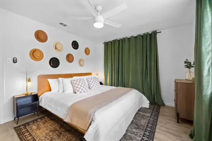 Cozy bedroom featuring a king-sized bed, blackout curtains for restful sleep, and unique hat décor that adds personality and style. The inviting atmosphere is perfect for unwinding, combining comfort with a touch of creative flair. A peaceful retreat