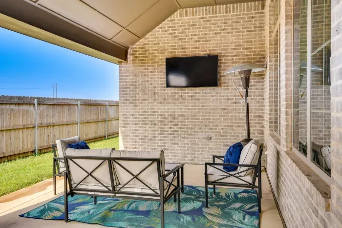Covered patio with outdoor seating and wall-mounted TV.