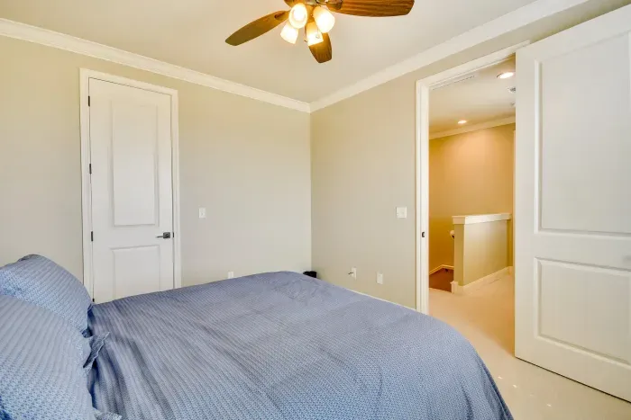 Cozy bedroom with plush bedding and ceiling fan.